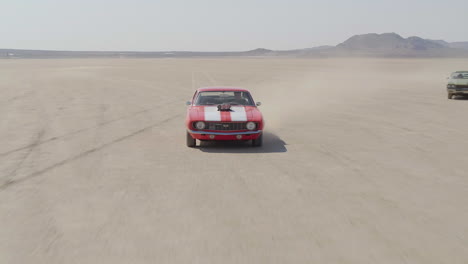 revealing shot of a group of muscle cars coming together and driving through the desert