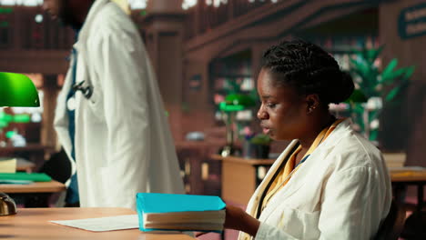 black medical student reading healthcare books at the campus library