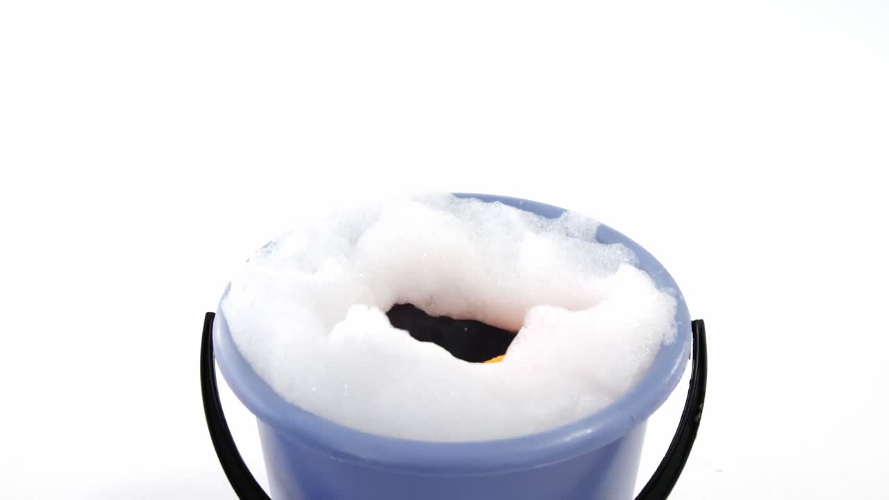 esponja de limpieza cayendo en un cubo de espuma de jabón