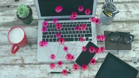 Animation-of-connected-icons-globe,-overhead-view-of-laptop,-cellphone,-spectacles-and-milk-on-table