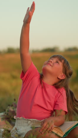 joven con camiseta rosa sentada al aire libre en la naturaleza, alegremente alcanzando para atrapar burbujas flotantes con una expresión lúdica, rodeada de vegetación, configuración de picnic