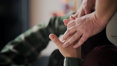 Vertical-close-up-video-of-two-middle-aged-men-LGBT-couple-holding-hands-while-communicating-in-a-modern-apartment-hands-clasping-each-other