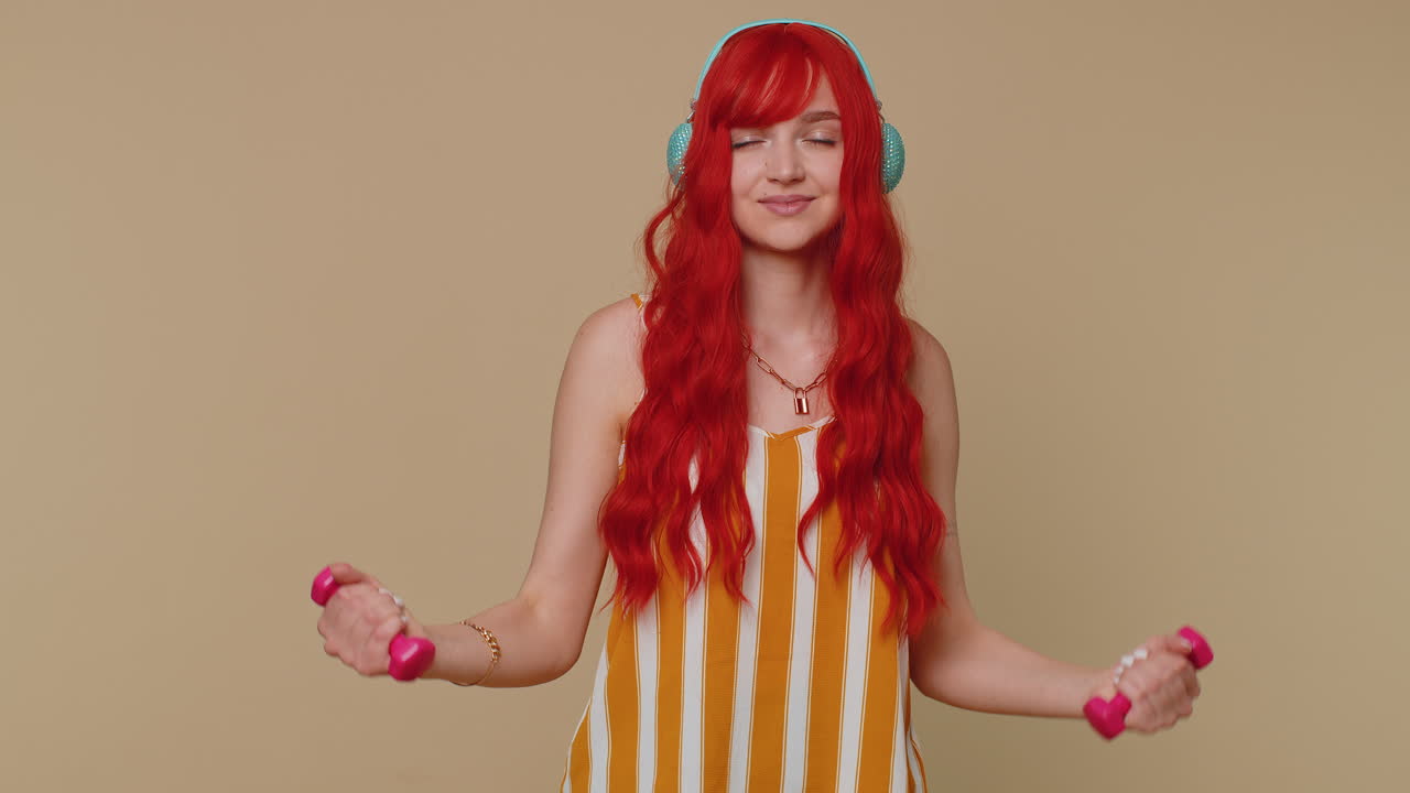 여자가 피트니스 덤벨을 만들고 운동을 하고 헤드폰으로 음악을 듣고 필라테스를 연습하고 건강 관리