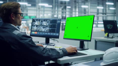 african american engineer using laptop computer and looking out of the office at a car assembly plant. vehicle factory line operator working at desk with computer with green screen display.
