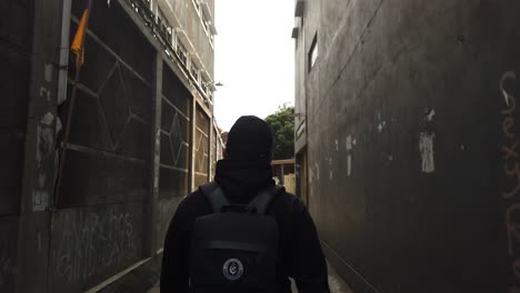 back-view-of-a-male-traveller-walking-through-an-alley