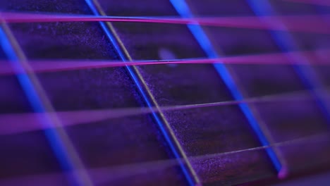 strings of acoustic guitar illuminated by neon lights