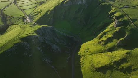 aerial view from winatts pass with a tilt up reveal of the town of castleton and the sunrise over the landscape in the peak district, uk