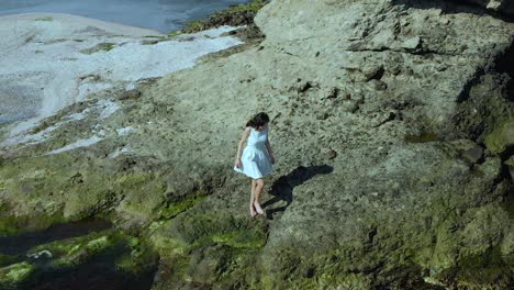 Toma-Aérea-En-Cámara-Lenta-De-Una-Chica-Guapa-Con-Vestido-Blanco-Caminando-Por-La-Playa-1