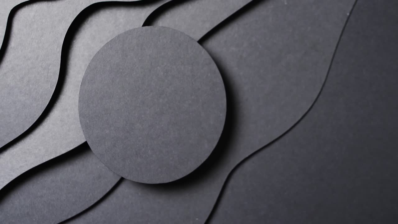 Video of close up of circle of black paper on waves cut out and copy space on black background