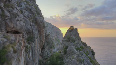 volando de cerca sobre los picos de las montañas revelando una puesta de sol y el mar mediterráneo en sa calobra, mallorca, españa