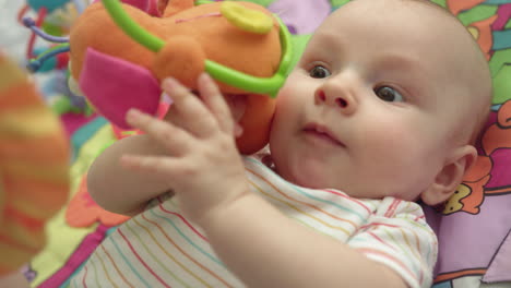 Close-up-of-infant-showing-tongue.-Portrait-of-cute-baby-playing-with-toys