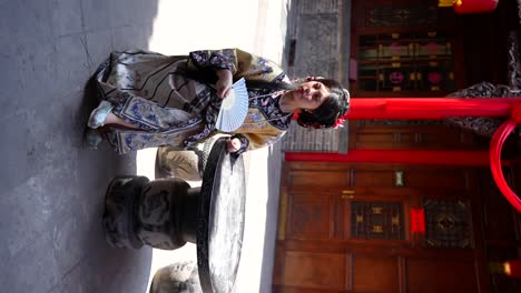 qing dynasty chinese girl in traditional clothing sits in a yard using a hand fan