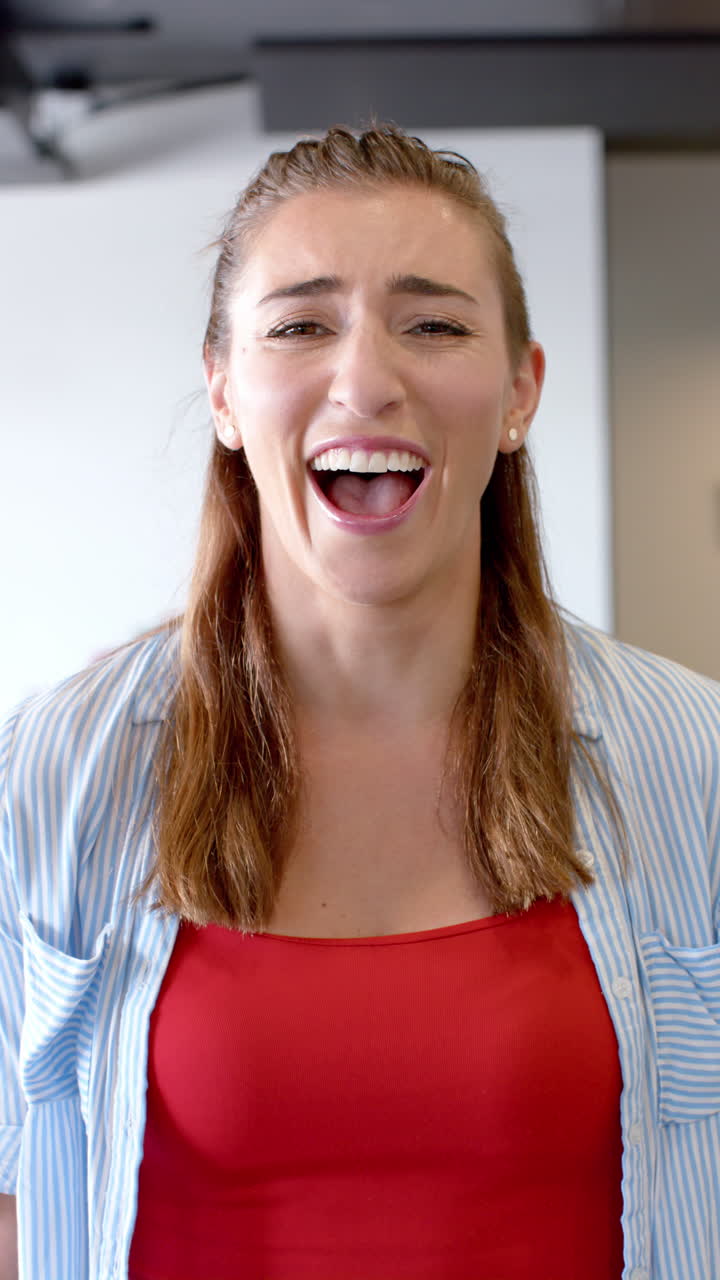Vertical video of portrait of happy caucasian businesswoman in office in slow motion