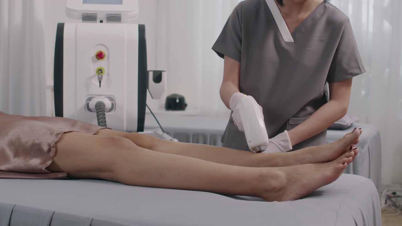 Female Specialist Removing Hair from Clients Legs with Laser