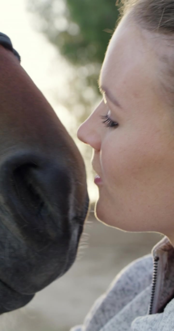 Young Woman Affectionately Kissing Her Horse Outdoors
