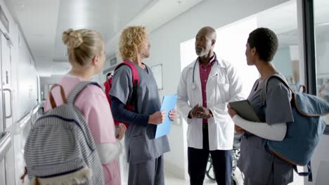 diverse doctors discussing work in corridor at hospital, slow motion