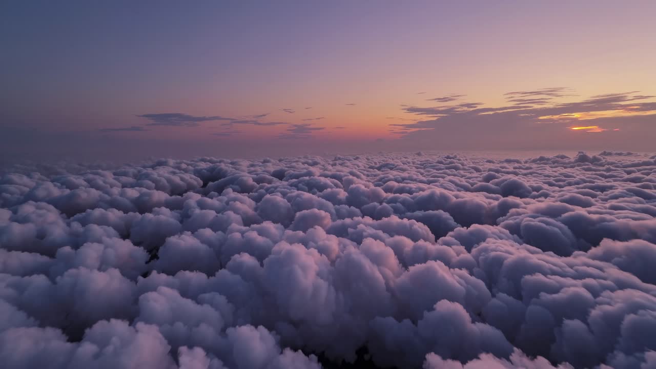 Aerial video captures a serene sea of fluffy clouds at sunset, with a wide-angle view