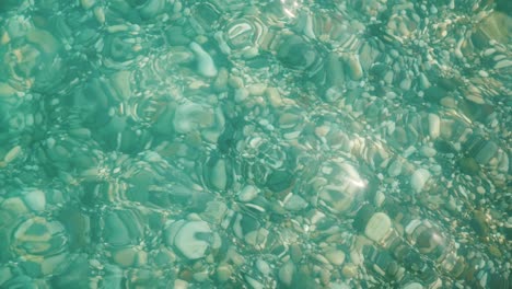 through the crystal clear sea water you can see a variety of sea stones on the sea coast