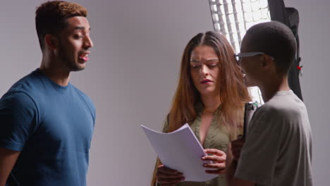 Film-Director-Talking-With-Male-And-Female-Actors-Holding-Scripts-Rehearsing-For-Shooting-Movie-Or-Video-In-Studio-8