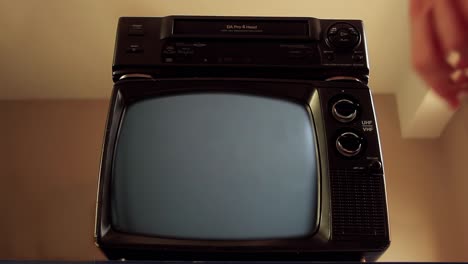hombre con la mano poniendo vhs en vcr y vieja televisión encendiendo pantalla verde. cerca. resolución 4k.