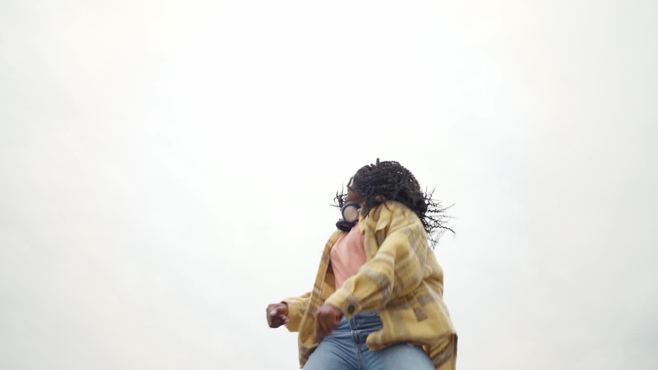Energetic black woman dancing on concrete border