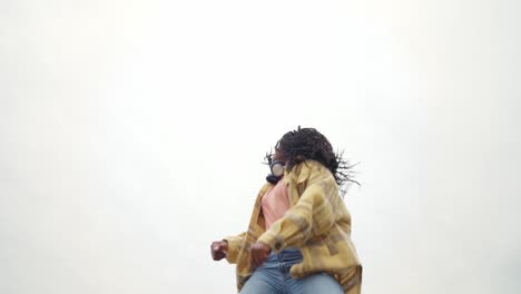 energetic black woman dancing on concrete border