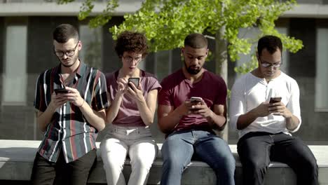 front view of focused friends using smartphones in park