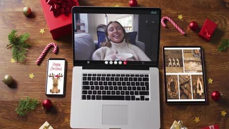 Happy-caucasian-woman-on-video-call-on-laptop,-with-smartphone,-tablet-and-decorations