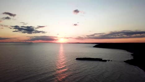 beautiful sunset over tranquil sea in santo tomas, menorca, spain - aerial static shot