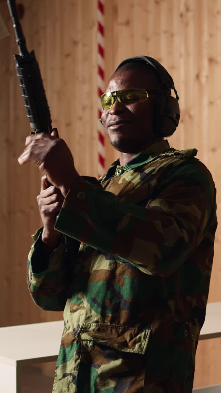 Vertical video Portrait of cheerful soldier doing training in shooting range, reloading rifle