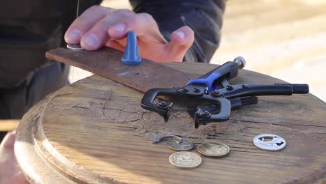 man cuts coins to make art at praça do comércio, terreiro do paço, right by the tagus river, in the center of lisbon, portugal.