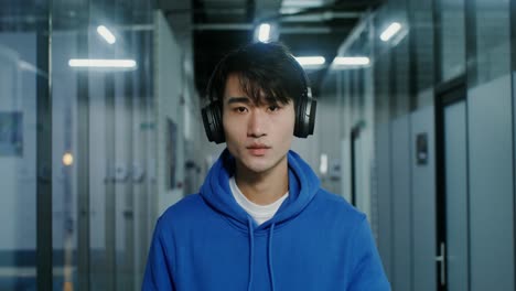 young man wearing headphones in an office corridor