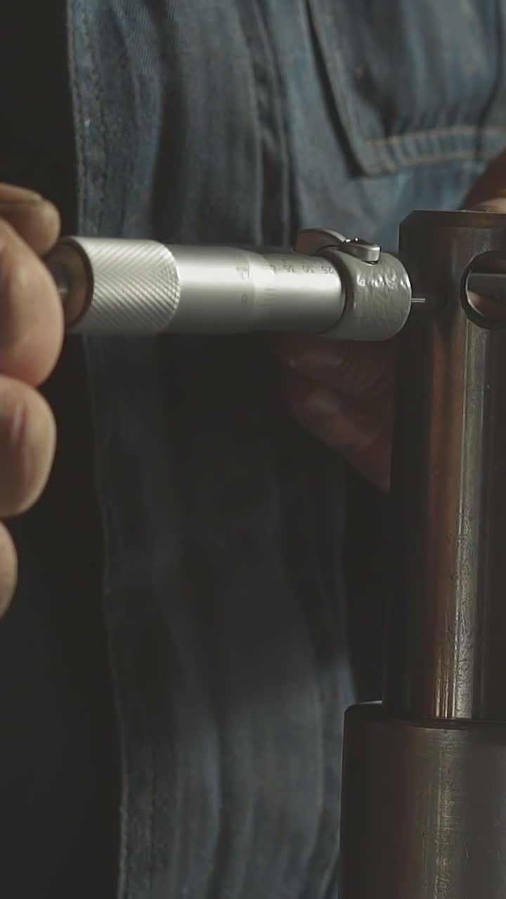 Worker connects detail to metal cylinder assembling machine tool in workshop closeup. Employee prepares mechanism to operate at production factory