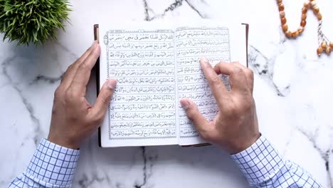 top view of young man reading holy book quran on table