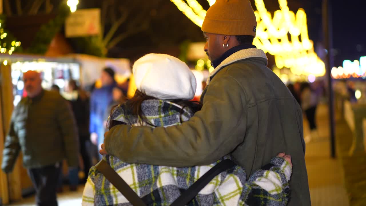 Couple embracing at a Christmas market at night