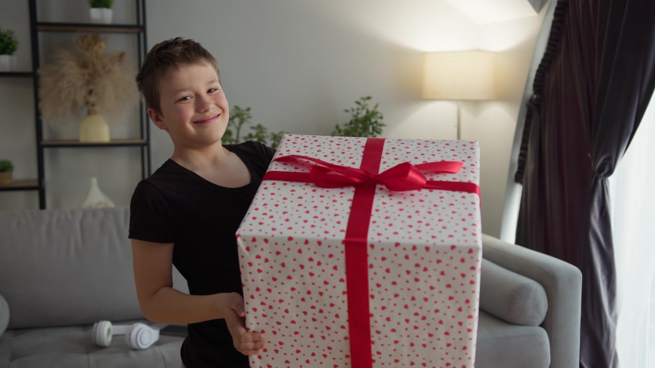 Un bambino trasporta con gioia grandi scatole regalo impacchettate attraverso un salotto moderno con un divano.