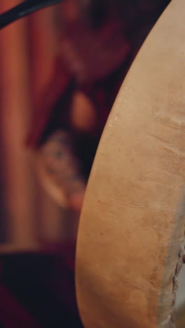 musician taps shamanic drum with furry stick in ail cabin closeup. siberian man conducts ancient mystical ritual. folk music and performance