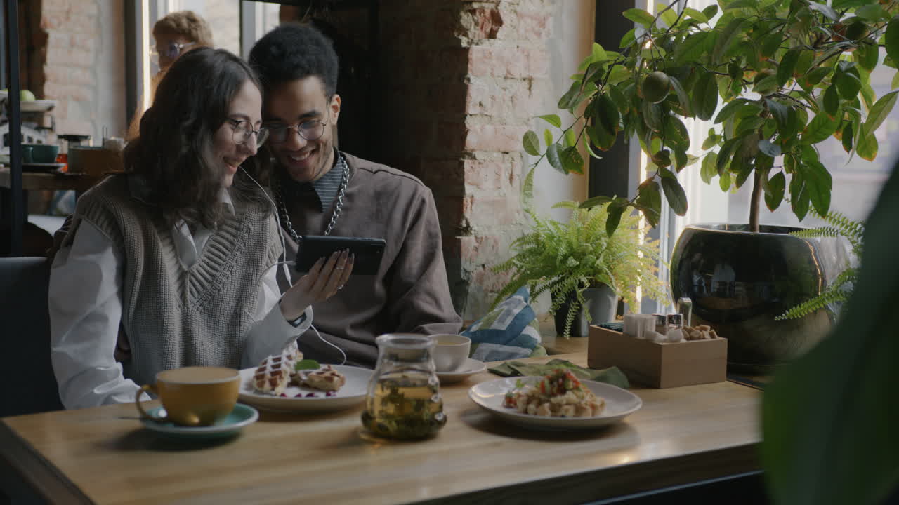 Coppia che consuma un pasto e usa lo smartphone in un bar