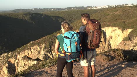 pareja de turistas con mochilas de campamento de pie en el acantilado