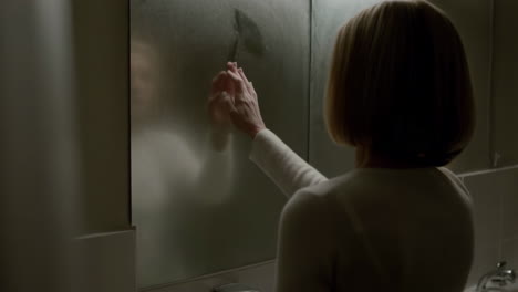 woman touching a foggy bathroom mirror