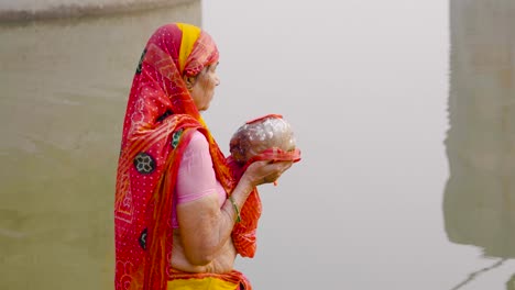 indian elderly woman praying to sun