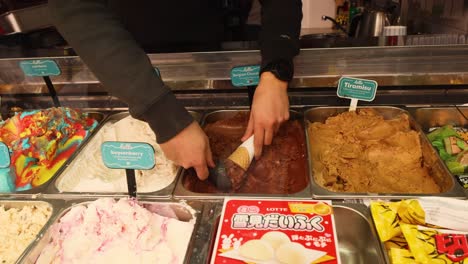 hand scooping chocolate tiramisu ice cream into cone