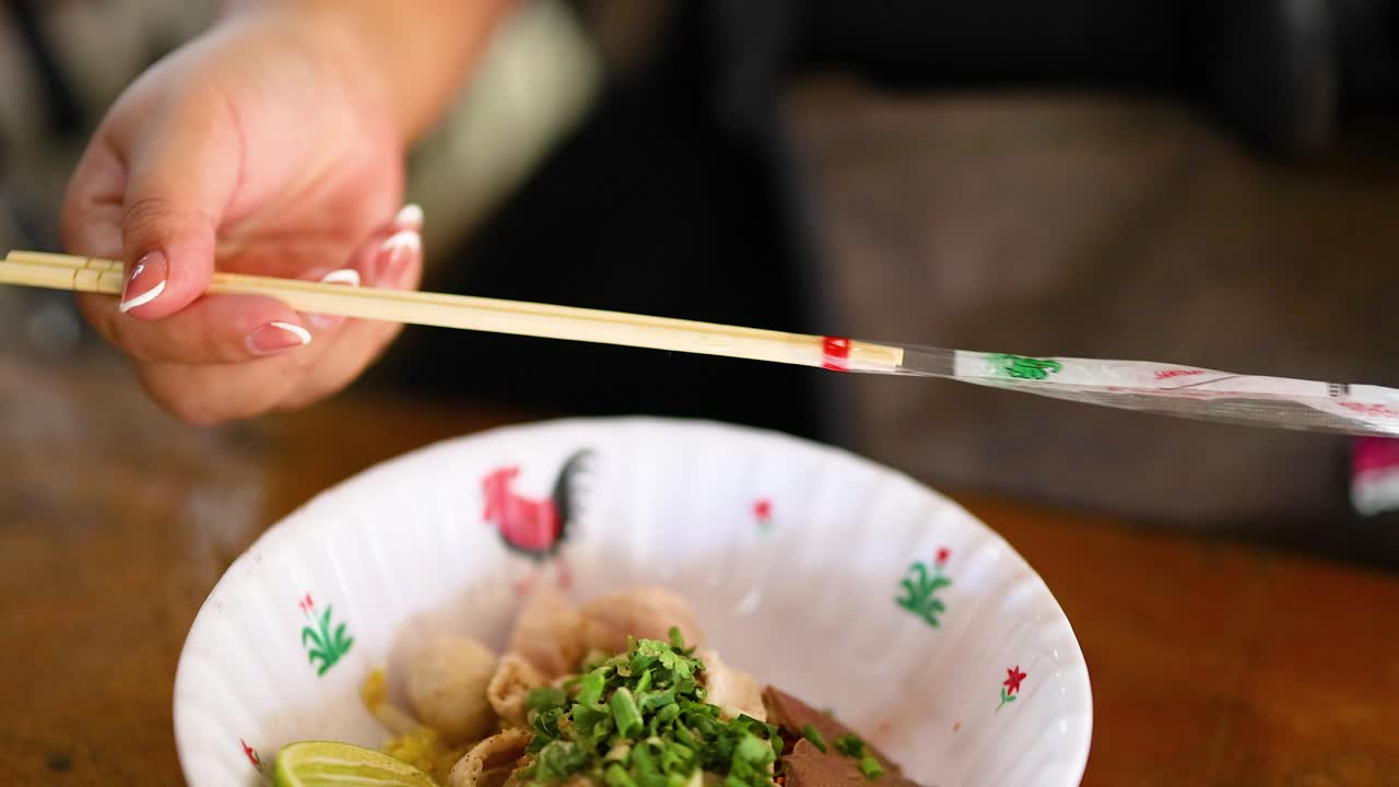 Chopsticks and spoon mix noodles with toppings