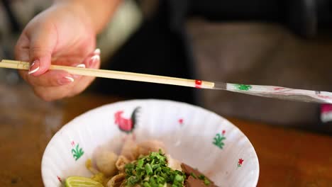 chopsticks and spoon mix noodles with toppings