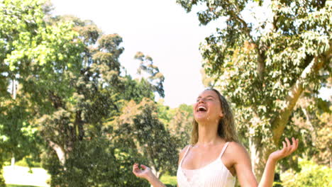 Blonde-woman-standing-in-slow-motion-while-receiving-water