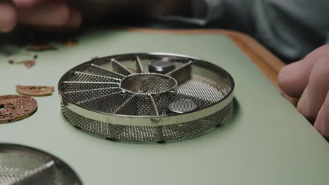 a watchmaker separating parts of a watch in a screen for cleaning - close up