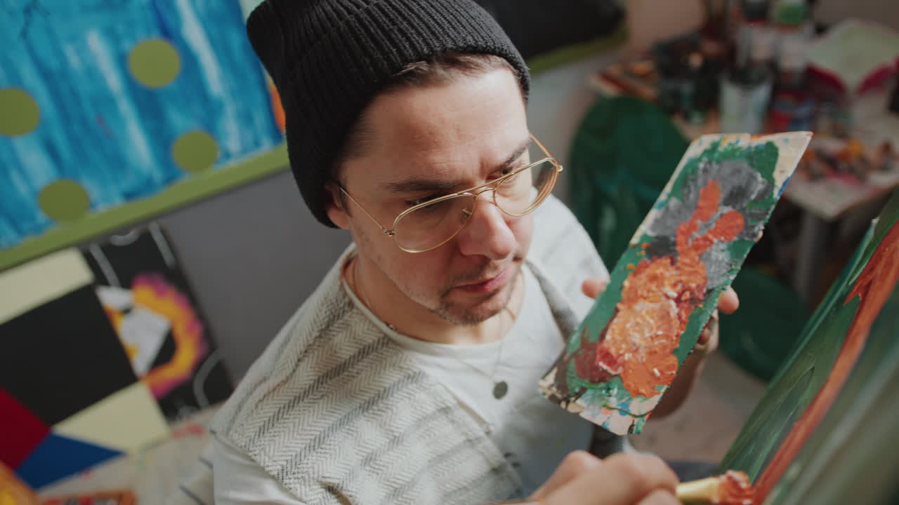 크리에이티브 스튜디오에서 팔레트와 으로 그림을 그리는 예술가