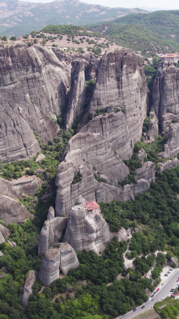 Vertical aerial tilt-up shot showing the monasteries of Meteora perched atop immense natural rock pillars in Greece