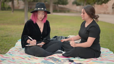 two young women having a discussion while doing makeup in a park