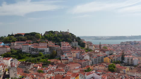 Carro-Aéreo-En-Vista-Del-Antiguo-Castillo-En-La-Colina-Sobre-Casas-Coloridas-En-El-Centro-Urbano-De-Lisboa